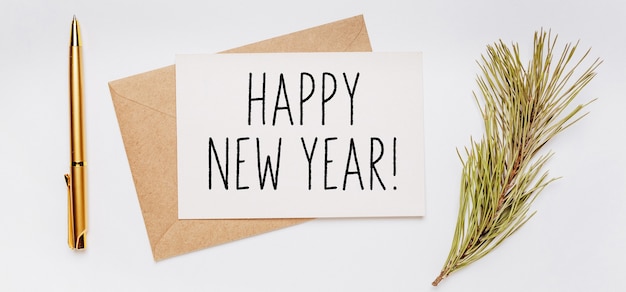 Frohes neues Jahr-Anmerkung mit Umschlag, Fichtenzweig und Goldstift auf weißem Hintergrund. Frohe Weihnachten und Neujahr Konzept