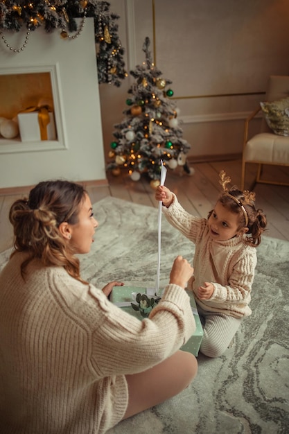 Frohes neues Jahr Familientraditionen junge Mutter und ihre Tochter haben Spaß zu Hause in der Nähe des Weihnachtsbaums und des Kamins