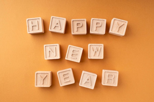 Frohes neues jahr ist auf holzwürfel geschrieben. holzwürfel mit buchstaben auf einem orangefarbenen hintergrund neujahrskarte