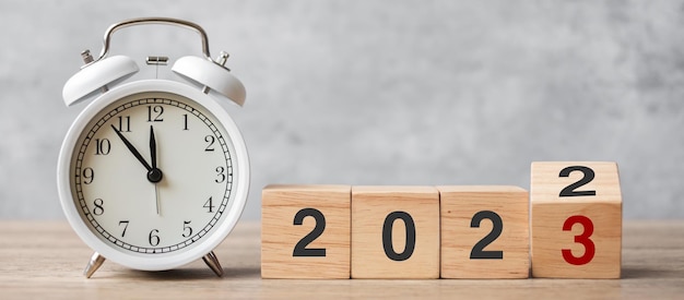 Frohes neues Jahr mit Vintage-Wecker und Umdrehen von 2022 auf 2023 Block Weihnachten Neuanfang Auflösung Countdown Ziele planen Aktion und Motivationskonzept