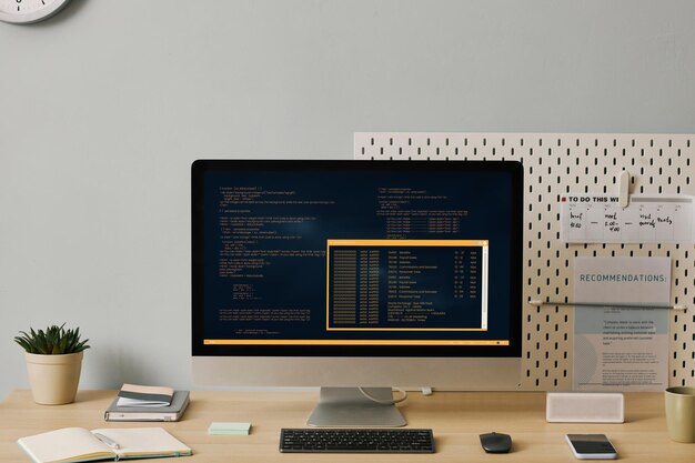 Frontansicht-Computer mit Codezeilen auf dem Bildschirm in minimalem Home-Office-Setup