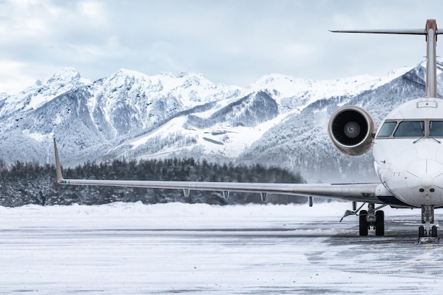 Frontansicht des Privatjets auf dem Vorfeld des Flughafens vor dem Hintergrund hoher malerischer Berge