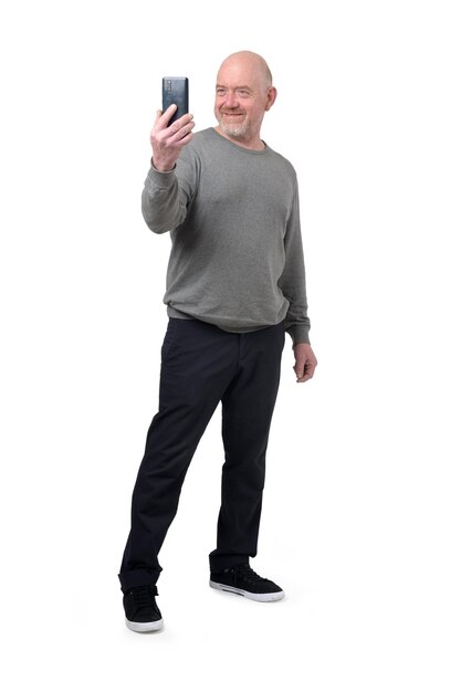 Foto frontansicht eines mannes, der ein selbstporträt mit einem smartphone auf weißem hintergrund macht