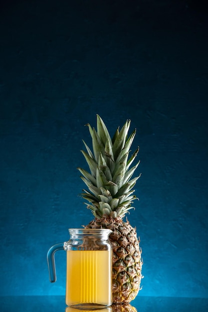 Frontansicht Glascocktailglas mit Saft und Cocktailschirm Ananas auf dunkelblauem Hintergrund