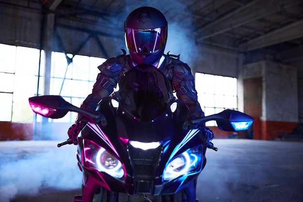 Frontansicht Porträt eines Motorradfahrers, der ein Sportmotorrad im Neonlicht fährt