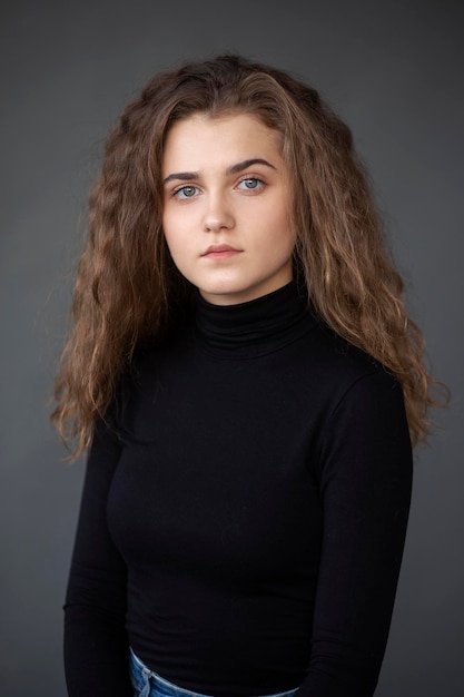 Frontbild Porträt eines Mädchens mit lockigem Haar auf grauem Hintergrund