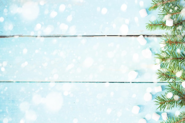 Fronteira de Natal com galho de abeto e marshmallows em fundo de madeira decorado com neve