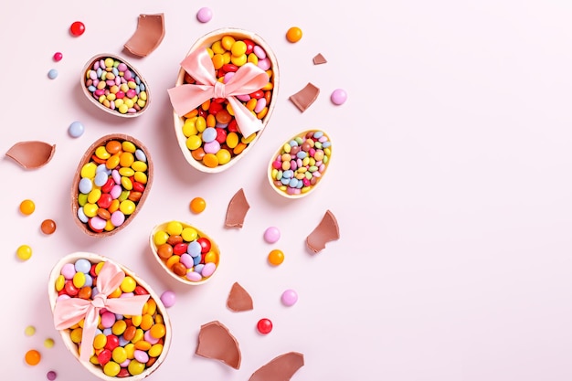 Foto fronteira de páscoa de chocolate com ovos de chocolate e doces coloridos em espaço de cópia rosa pastel tratamentos tradicionais de páscua de fundo de férias planas