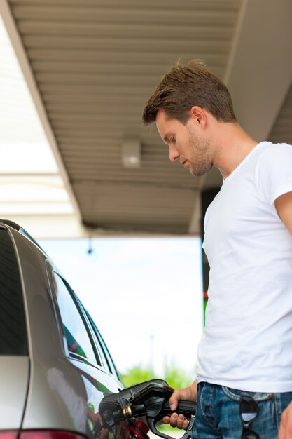 Froschperspektive des mannes auto an der tankstelle betankend