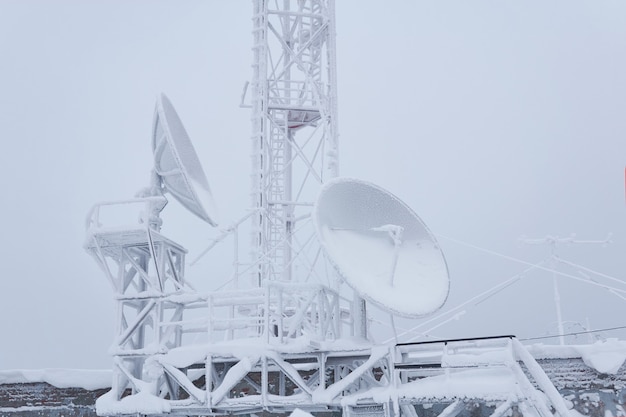 Frostige Parabolantennen und Mobilfunkmast auf dem Dach der Basisstation im Hochland