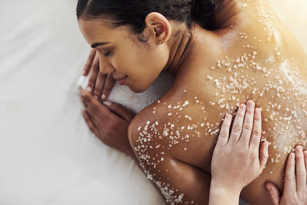 Frotar la piel muerta para revelar un nuevo yo Foto de una mujer joven que recibe un masaje exfoliante en un spa