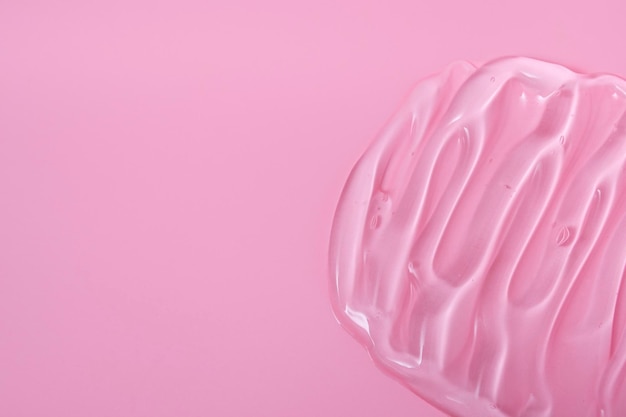 Frotis cosméticos de gel para el cuidado de la piel sobre un fondo rosa crema peeling leche loción gotas textura Primer plano con espacio de copia