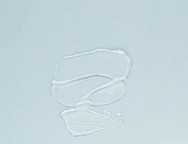 Frotis de crema transparente para la cara y el cuerpo sobre un fondo azul.