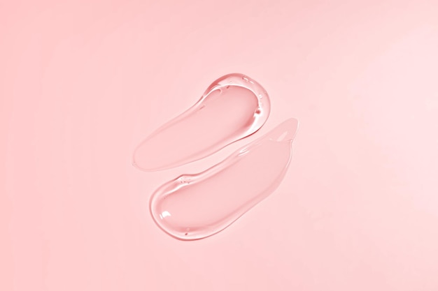 Frotis de gel líquido aislado sobre fondo beige Mancha cosmética de belleza como loción de aloe transparente pura jalea facial limpiador de suero gel de ducha o champú vista superior