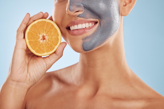 Frucht-Gesichtsmaske und Frau mit Orange für Vitamin-C-Hautpflege oder Bio-Behandlung isoliert auf blauem Studiohintergrund Zitrushaut und junge weibliche Person mit Gesichts-Wellness-Ernährung und Entgiftung