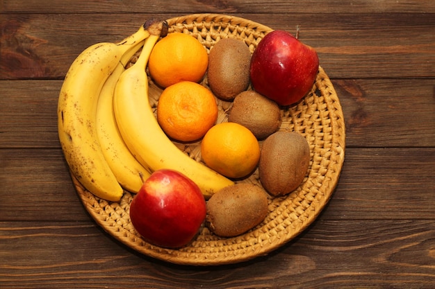 Fruchtbanane-Kiwi-Apfel-Mandarinen liegen in einer Weidenplatte