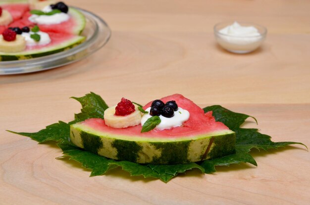 Fruchtdessert aus Wassermelone und Beeren auf einer grünen Blattnahaufnahme