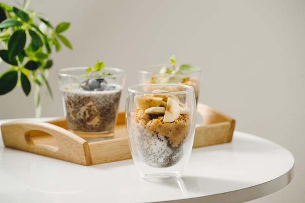 Fruchtjoghurtparfait mit Müsli und Chiasamen für gesundes Frühstück auf Holztisch