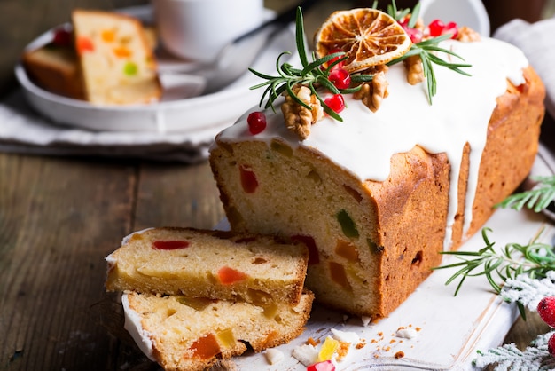 Fruchtkuchen wischte geschnitten mit Zuckerglasur, Nüssen, Kerngranatapfel und trockener orange Nahaufnahme ab. Weihnachts- und Winterferien hausgemachten Kuchen