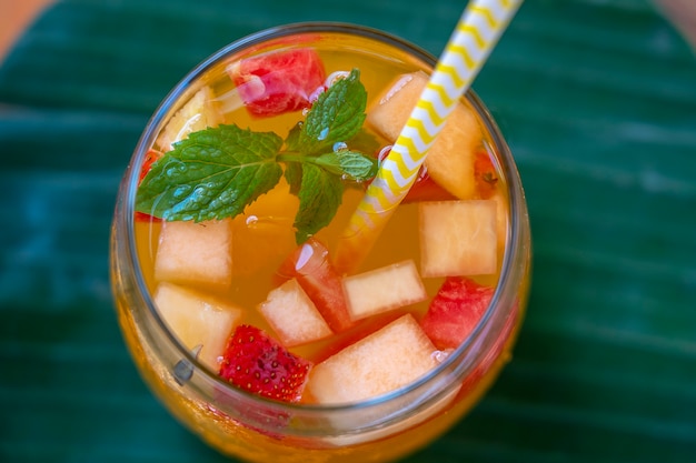 Fruchtlimonade aus roten Erdbeeren, Melonen und Ananas im Glas. Nahaufnahme. Erfrischendes Getränk aus Fruchtstücken