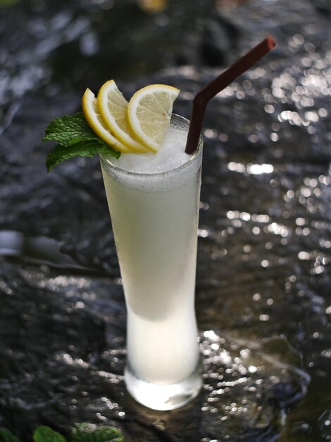 Foto fruchtsaft frucht-smoothie fruchtsaft fruchtsaft im glas auf einem felsen in der nähe des wasserfalls platziert