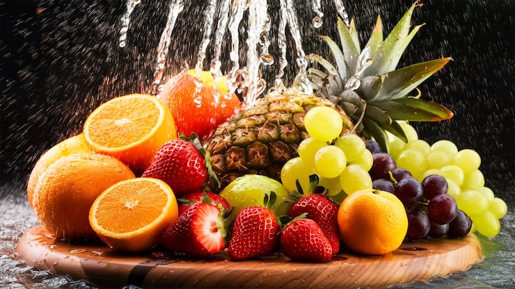 Früchte, die auf schwarzen Hintergrund in Wasser spritzen