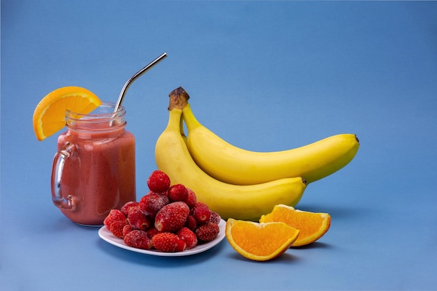 Früchte und Beeren auf hellblauem Hintergrund Eine Reihe von Bananen, Orangen und Erdbeeren für Smoothie