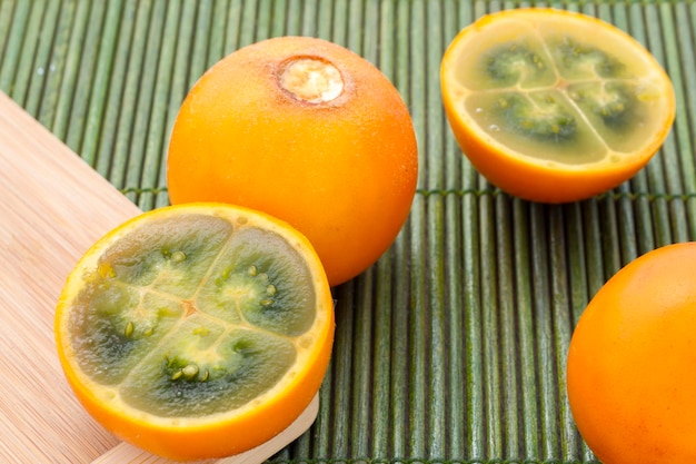 Früchte und Scheiben von Lulo oder Naranjilla auf dem Holztisch Solanum quitoense