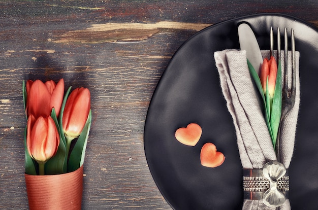 Frühjahrmenükonzept mit frischen Tulpen und Herzdekoration auf dunklem Holz