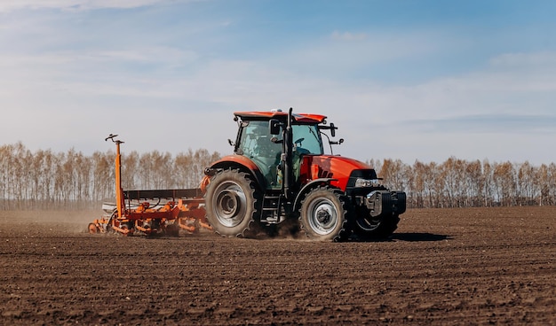 Frühjahrsaussaat Bauer mit einem Traktor sät Maissamen auf seinem Feld Anpflanzen von Mais mit gezogenem Pflanzer Landwirtschaftliche Aussaat Das Konzept der Landwirtschaft und der landwirtschaftlichen Maschinen