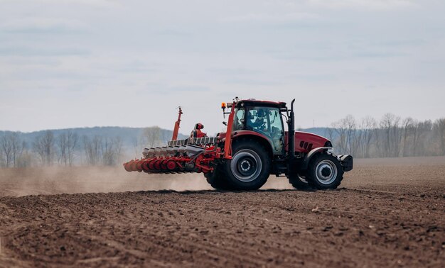 Frühjahrsaussaat Bauer mit einem Traktor sät Maissamen auf seinem Feld Anpflanzen von Mais mit gezogenem Pflanzer Landwirtschaftliche Aussaat Das Konzept der Landwirtschaft und der landwirtschaftlichen Maschinen