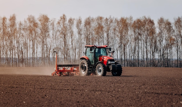 Frühjahrsaussaat Bauer mit einem Traktor sät Maissamen auf seinem Feld Anpflanzen von Mais mit gezogenem Pflanzer Landwirtschaftliche Aussaat Das Konzept der Landwirtschaft und der landwirtschaftlichen Maschinen