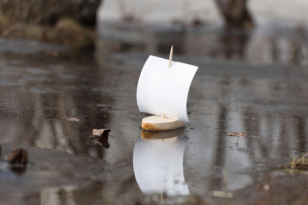 Frühling Ein Holzboot mit Segel schwimmt entlang einer Waldpfütze