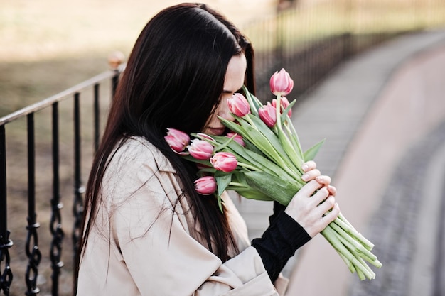 Frühling Selbstliebe Selbstpflege offenes Porträt einer glücklichen Frau mit Tulpenblumenstrauß im Freien schön