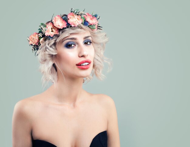 Frühlings-Frauen-Mode-Modell mit Rosen-Blumen auf dem Kopf. Süßes Mädchen mit blonder Bob-Frisur und Make-up