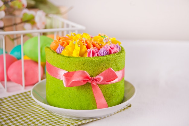 Frühlings Ostern festlichen Tisch. Kleiner grüner Kuchen mit Buttercremeblumen und bunten Eiern