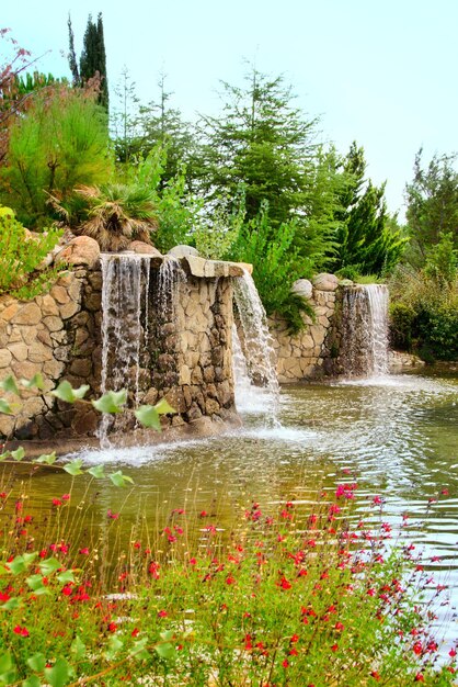 Frühlingsansicht eines Parks mit Teich, Blumen und mehreren Wasserfällen in Arroyomolinos (Spanien).