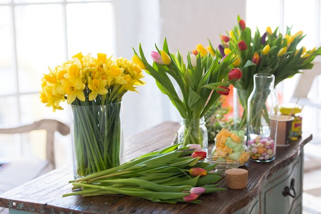 Frühlingsblumen auf einem Holztisch. Natürliches Licht in Innenräumen mit geringer Schärfentiefe