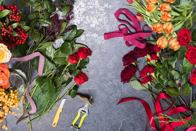 Frühlingsblumen auf einem Steintisch. Das Konzept der Herstellung von Rosensträußen, Tulpen. Florist am Arbeitsplatz