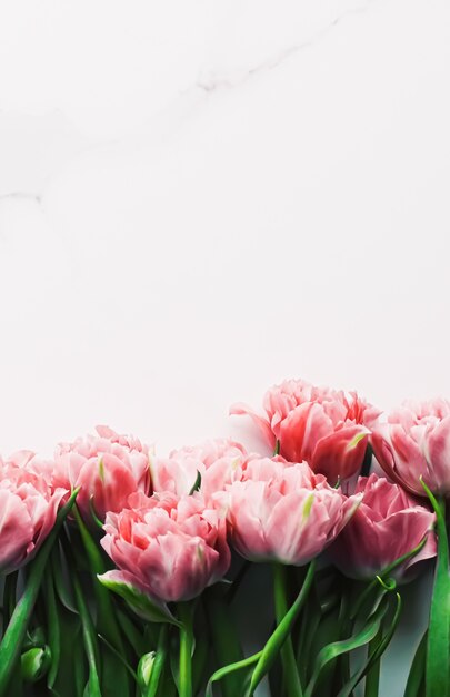 Frühlingsblumen auf Marmorhintergrund als Weihnachtsgeschenk-Grußkarte und florales Flatlay-Konzept