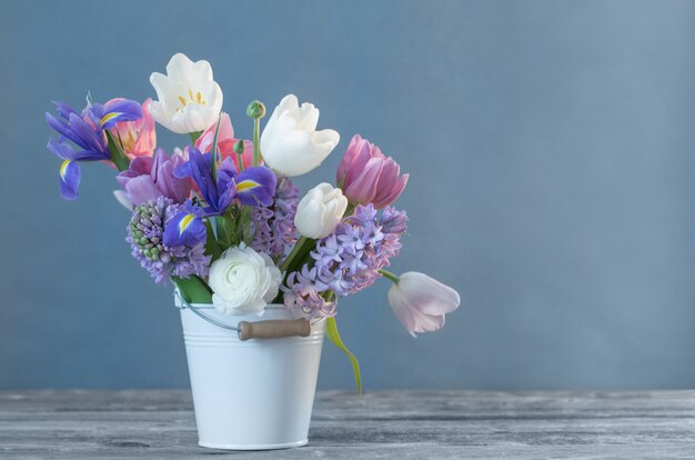 Frühlingsblumen im Eimer auf blauem Hintergrund