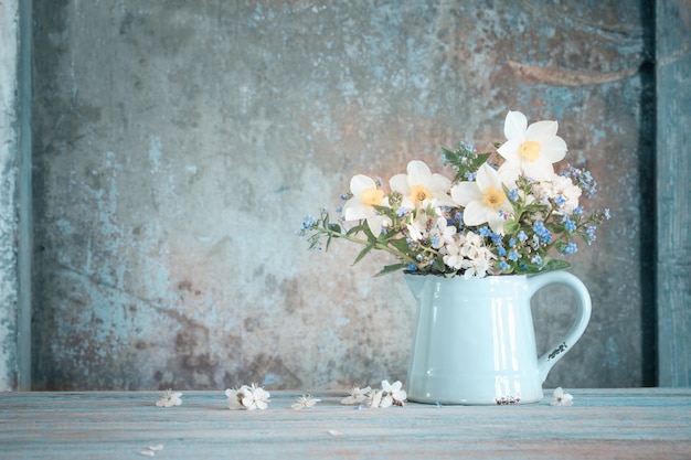 Frühlingsblumen im Krug auf altem gemaltem hölzernem Hintergrund