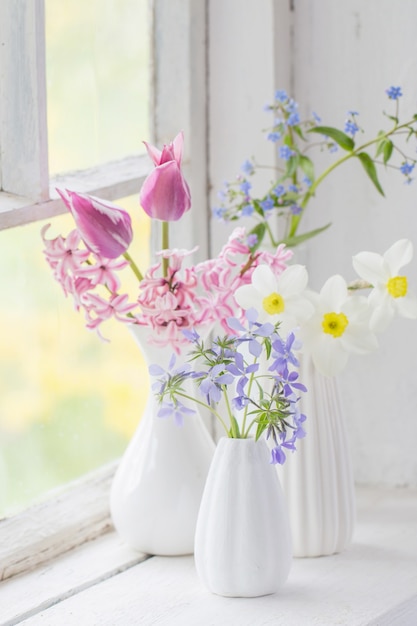 Frühlingsblumen in weißer Vase auf altem Fensterbrett