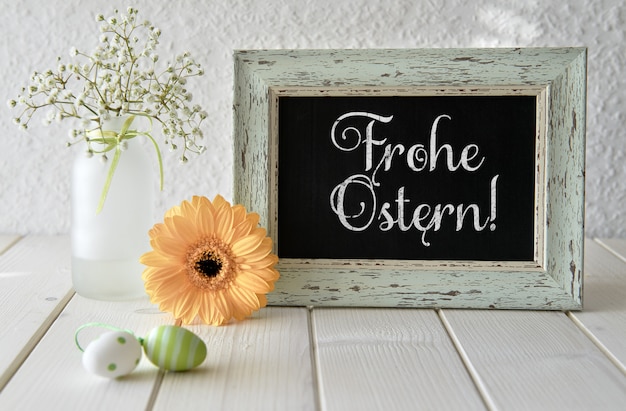 Frühlingsblumen, Ostern-Dekorationen und eine Tafel auf weißer Tabelle, Text