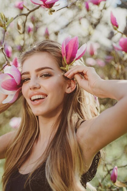 Frühlingsfrau mit Blumen Glücklicher Frühlingsurlaub Blühend Schönes Mädchen mit rosa Blumen Schönheitstag im Frühling Glücklicher sonniger blühender Frühling