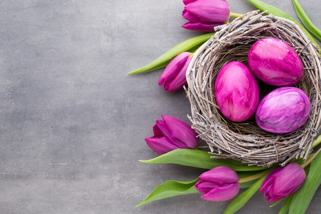 Frühlingsgrußkarte. Ostereier im Nest. Frühlingsblumen Tulpen.