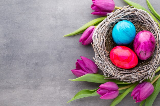 Frühlingsgrußkarte. Ostereier im Nest. Frühlingsblumen Tulpen.