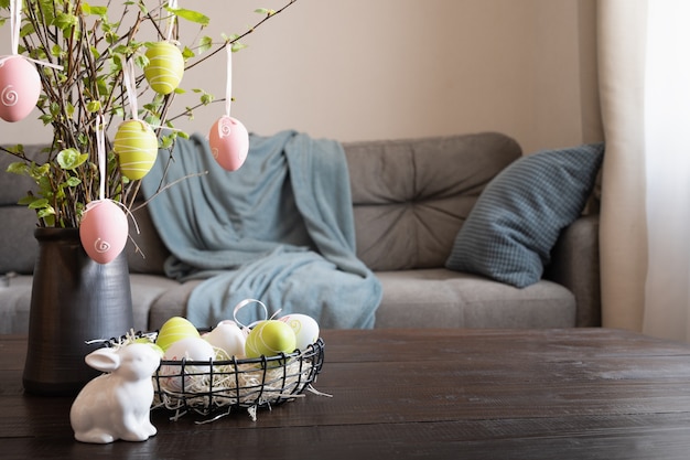 Foto frühlingshausinnenraum mit osterbaum und vase mit bunten eiern.