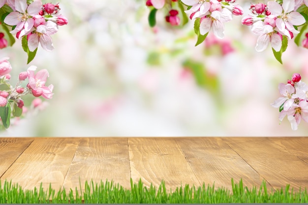 Frühlingshintergrund mit blühender rosa Apfelzweiggrenze und leerer Holztischplatte