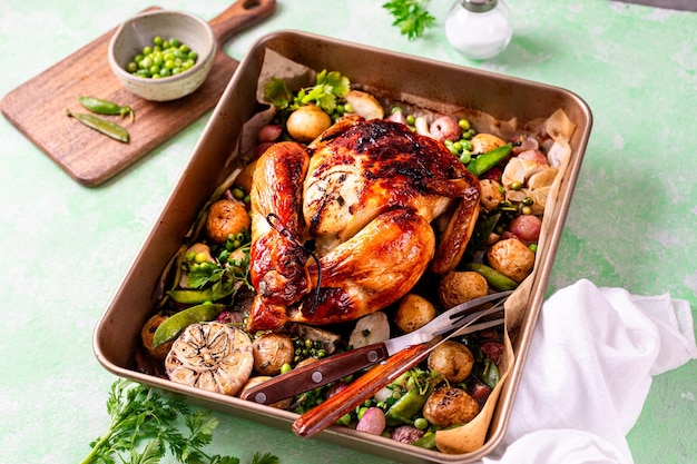 Foto frühlingshühnchen, gebacken mit rettichen und grünen erbsen in einem topf auf grünem hintergrund